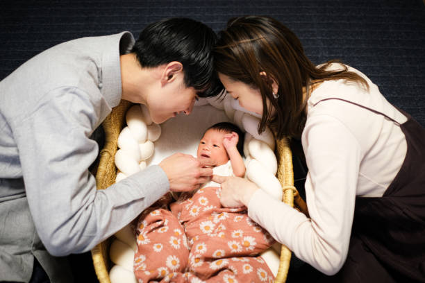 生まれたばかりの赤ちゃんを見ている母と父親 - 子育て ストックフォトと画像