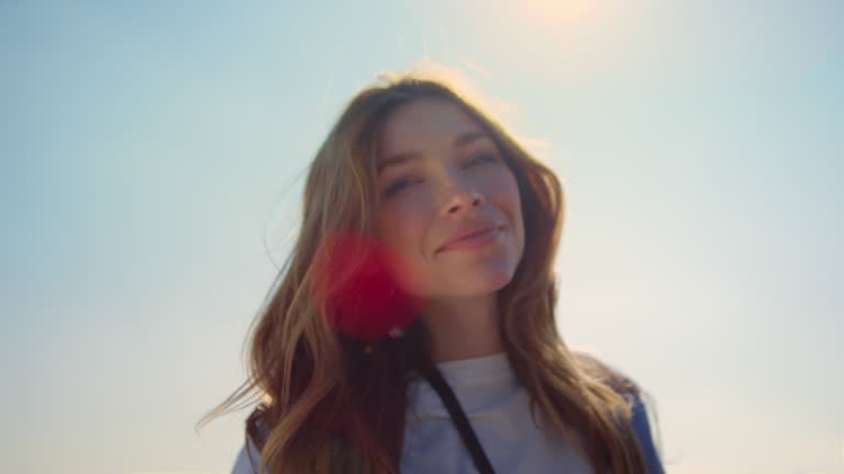 Portrait of beautiful woman in sunlight. Blue-eyed girl face in sunbeams outdoor