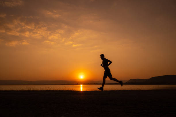 istock a man running Silhouette sunset at lake and Mountain 1365277930