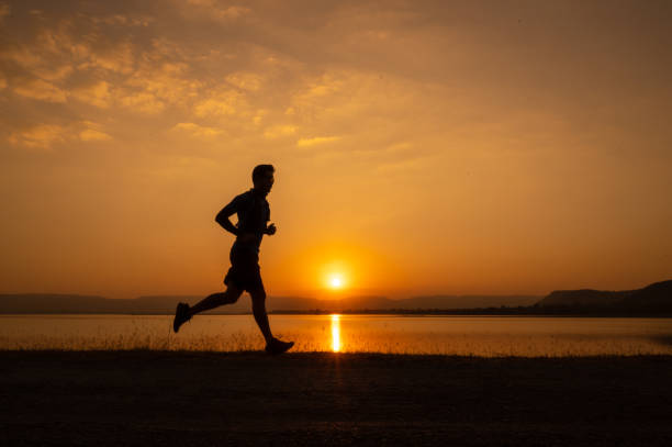 istock a man running Silhouette sunset at lake and Mountain 1365277937