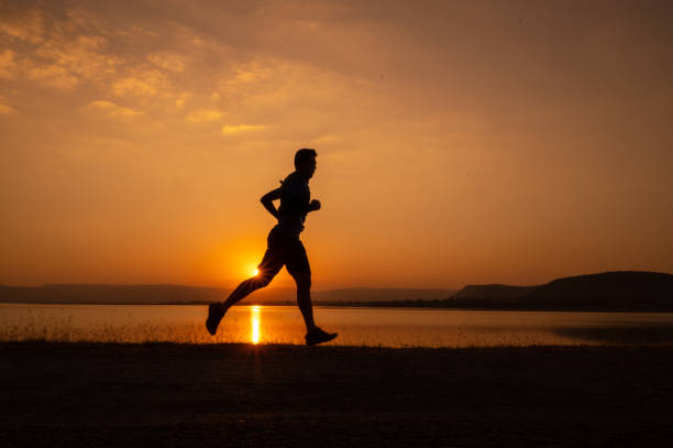 istock a man running Silhouette sunset at lake and Mountain 1365277939