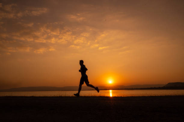 istock a man running Silhouette sunset at lake and Mountain 1365277944