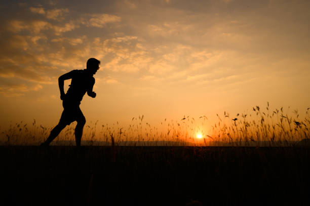 istock a man running Silhouette sunset at lake and Mountain 1365277945