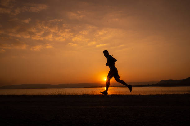 istock a man running Silhouette sunset at lake and Mountain 1365277947