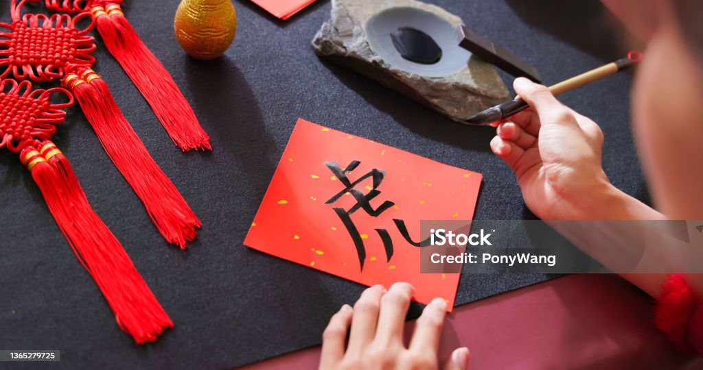 Writing spring festival couplet back view of asian woman write spring festival couplet to celebrate Chinese new year with word meaning Tiger Chinese New Year Stock Photo