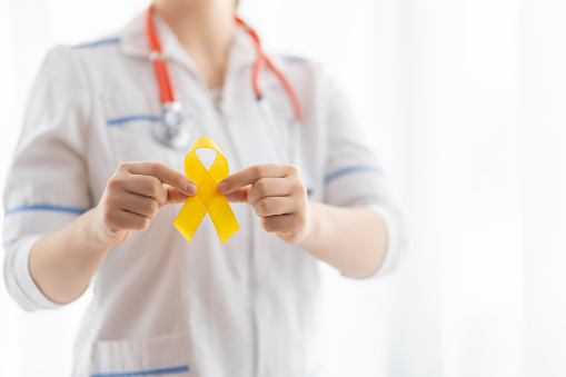 World Childhood cancer Day.  Doctor with golden ribbon.