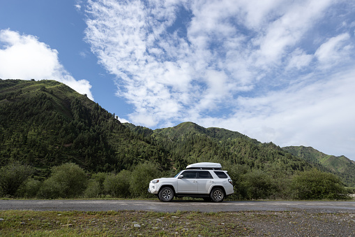 Driving off road car in high altitude forest mountains