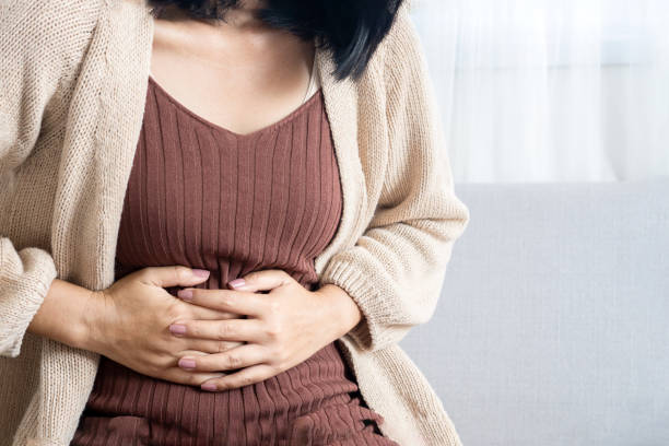 istock woman suffering from stomachache, pms hand holding her belly 1365289700