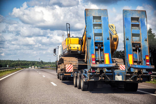 istock Transporting a heavy excavator in a truck trailer. Highway heavy oversized cargo transportation, industry. Copy space for text 1365290822