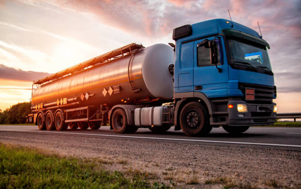 un camion moderno blu con un semirimorchio cisterna trasporta merci pericolose sullo sfondo del tramonto serale. il concetto di trasporto di carichi liquidi, classe di pericolo adr. industria - fuel tanker foto e immagini stock