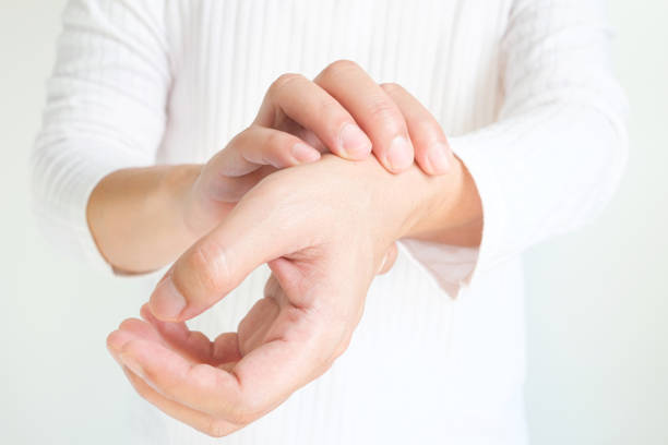 The man touches the wrist and thumb. He squeezes the knuckle of the thumb and wrist. He suffered a tendon injury, arthritis in his wrist, and de quervain's disease. stock photo