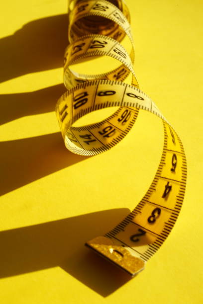 istock Yellow measuring tape on the sunny table closeup. Summer style with shadows 1365291750