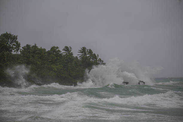 spruzzi di mare e surf sulle rocce in una tempesta con onde alte sul ciclone tropicale - tempesta tropicale foto e immagini stock