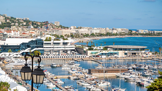 View of the sea port of Cannes, France. Moored yachts, modern buildings, greenery Mediterranean sea