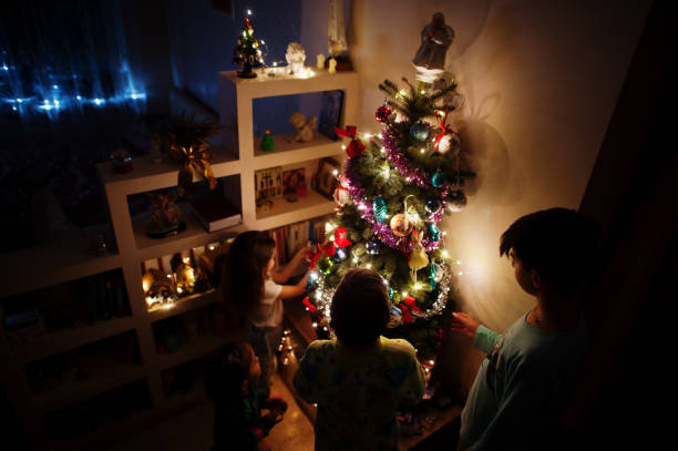 istock Kids looking on Christmas tree with shining garlands on evening home. 1365298475