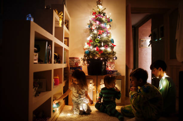 istock Kids looking on Christmas tree with shining garlands on evening home. 1365298492