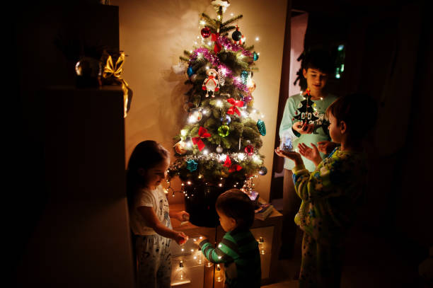 istock Kids looking on Christmas tree with shining garlands on evening home. 1365298500