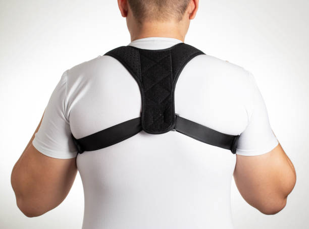 istock A man in a white T-shirt with a black posture corrector on a white background. Back pain and problem correction concept, treatment 1365298873