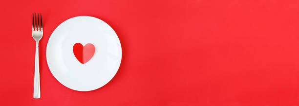 istock Heart on a white plate with fork on the red background 1365303069