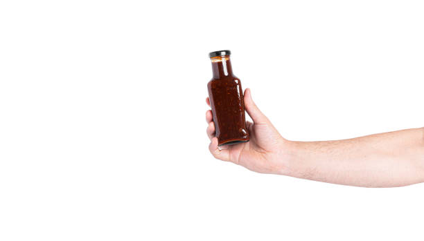 istock Sauce in a bottle isolated on a white background. Bottle in hand 1365305851