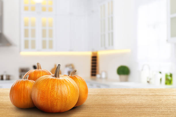 istock Fresh pumpkins on wooden table in kitchen. Space for text 1365306078