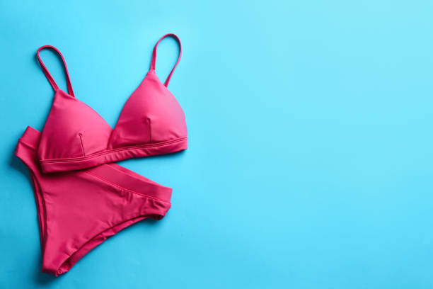istock Beautiful pink bikini on light blue background, top view. Space for text 1365306975