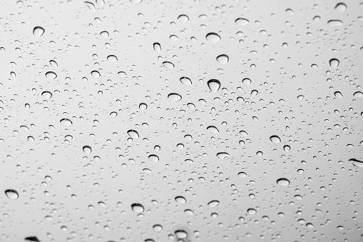 White drops of rain on a window glass in the city. Image of raindrops texture background.