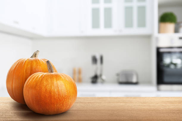 istock Fresh pumpkins on wooden table in kitchen. Space for text 1365308447