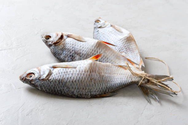 istock Dried salty river fish tied with twine on a light concrete background. 1365308628