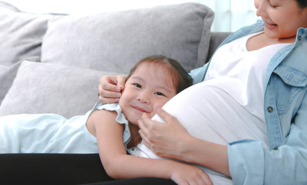 la bambina felice abbraccia la madre incinta - human pregnancy toddler child mother foto e immagini stock