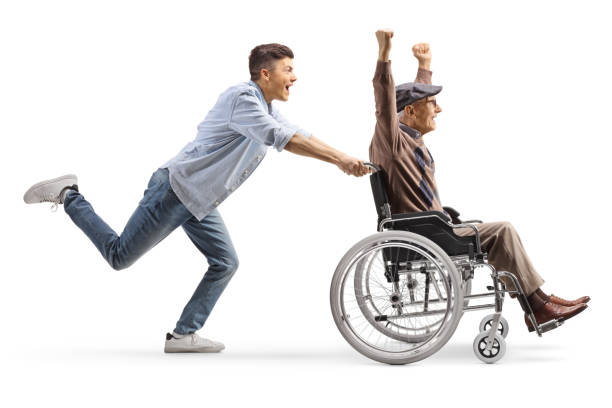 photo de profil d’un jeune homme courant et poussant un homme âgé heureux dans un fauteuil roulant - physical injury men orthopedic equipment isolated on white photos et images de collection