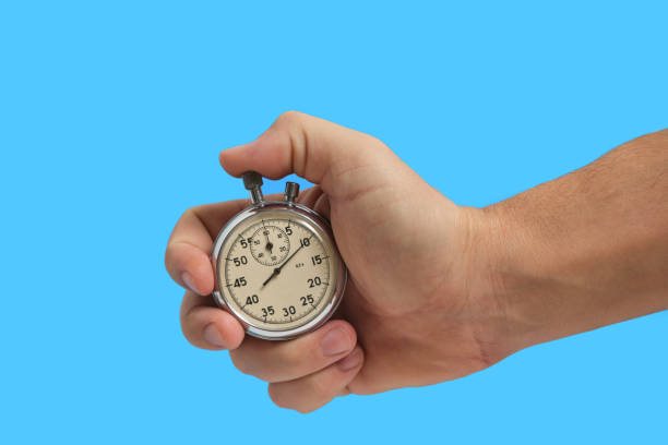 istock Man hand holding stopwatch on blue background. 1365311244