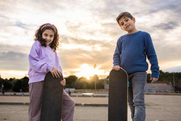 istock Two kids with a skate board at sunset 1365312589