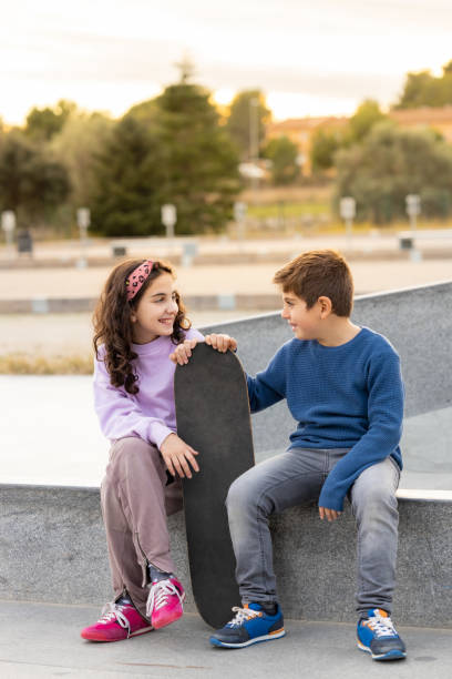 istock Two kids with a skate board at sunset 1365312592