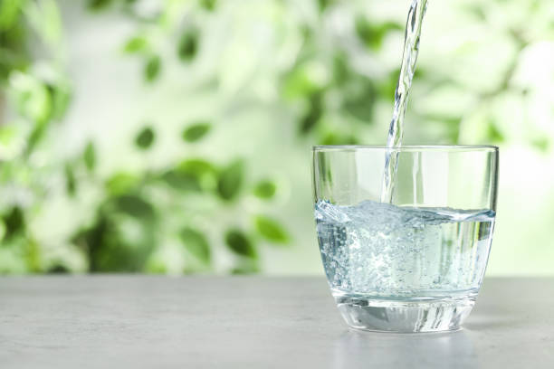 istock Pouring water into glass on grey table outdoors, space for text. Refreshing drink 1365313004