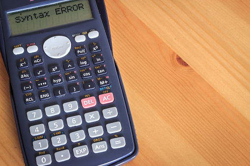 Blue digital calculator on wooden table background with copy space. Syntax error text on calculator screen.