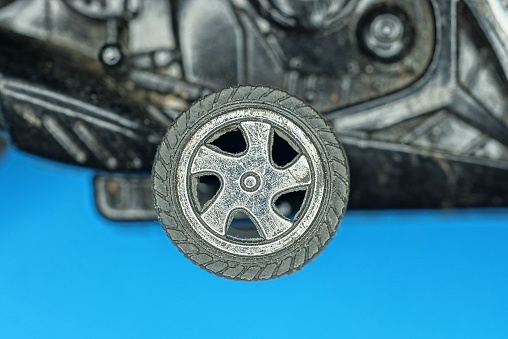 one old plastic small gray black wheel on an old toy on a blue background