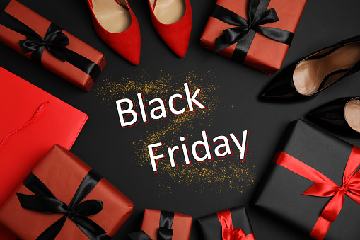 Flat lay composition with stylish women's shoes, gift boxes and phrase Black Friday on dark background