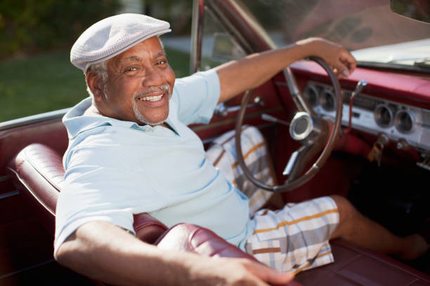istock Smiling older man driving convertible 1365315545