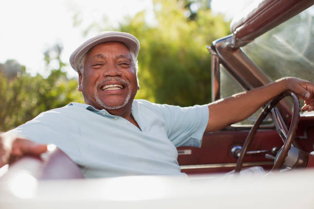 istock Smiling older man driving convertible 1365315583