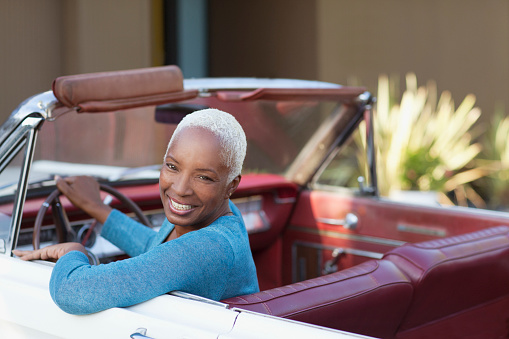 Smiling older woman driving convertible