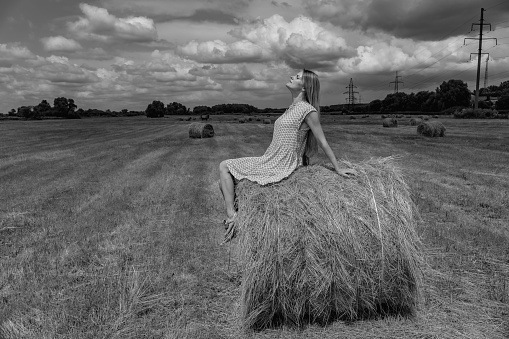 Field. The woman lies on the hay in the field.