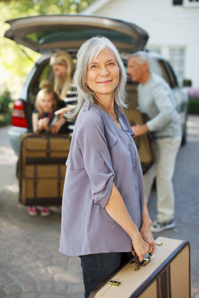 istock Woman carrying suitcase to trunk 1365315873