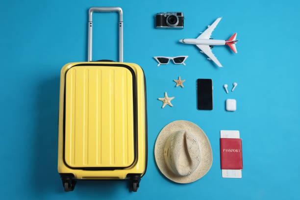 istock Flat lay composition with suitcase and travel accessories on light blue background. Summer vacation 1365317756