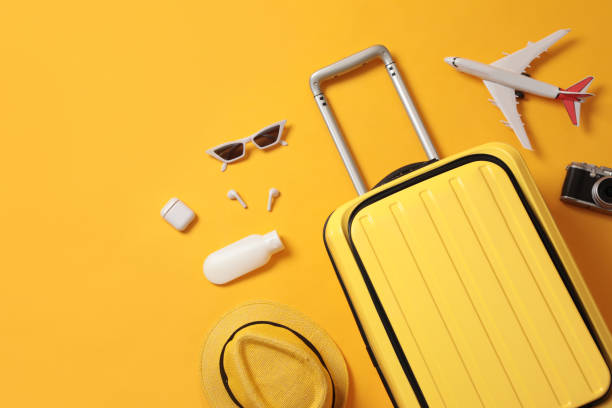 istock Flat lay composition with suitcase and travel accessories on yellow background. Summer vacation 1365318192