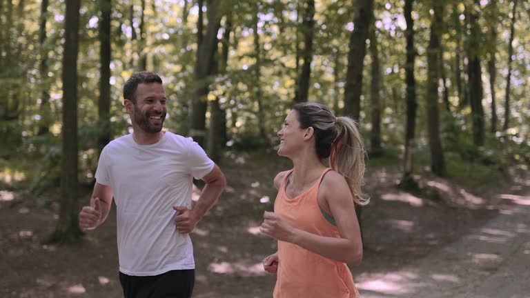 Happy athletic couple talking while running in nature.