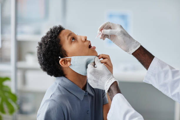 Oral Vaccination Drops Side View Side view of doctor dropping liquid in mouth of African-American girl during oral vaccination in clinic child liquid medicine stock pictures, royalty-free photos & images