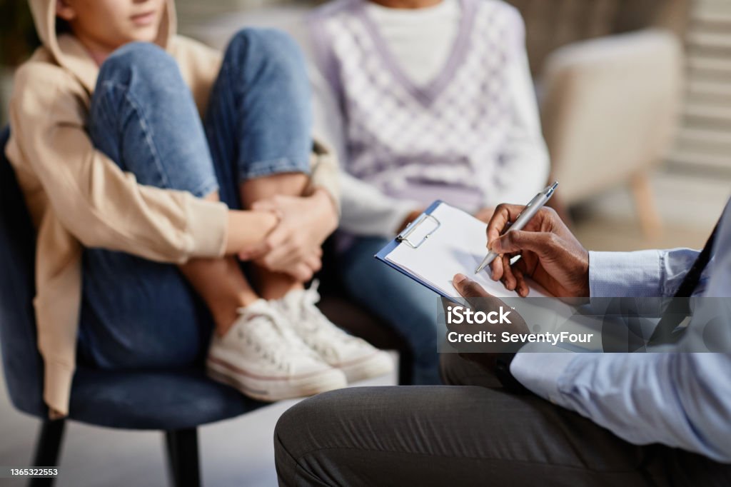 Therapy Session for Teens Close Up Close up of African-American psychologist taking notes on clipboard in therapy session for children Mental Health Stock Photo