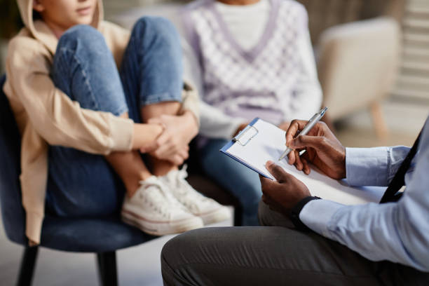 Therapy Session for Teens Close Up Close up of African-American psychologist taking notes on clipboard in therapy session for children mental health stock pictures, royalty-free photos & images