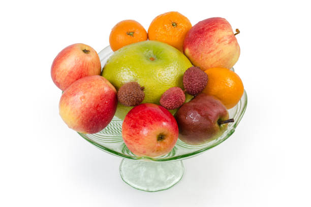 Different fresh washed fruits in a vintage green glass vase for fruits on a white background